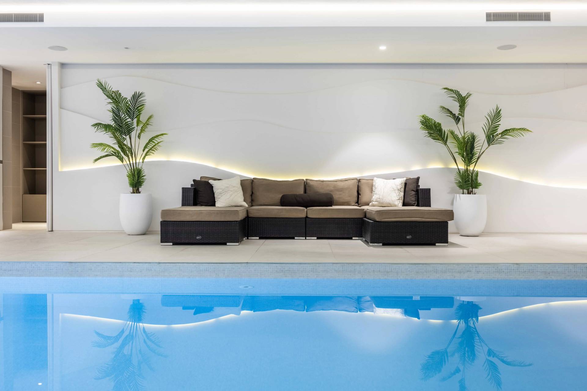 Indoor pool seating area featuring brown leather lounge chairs set beside textured stone walls, Love Locations WD7.