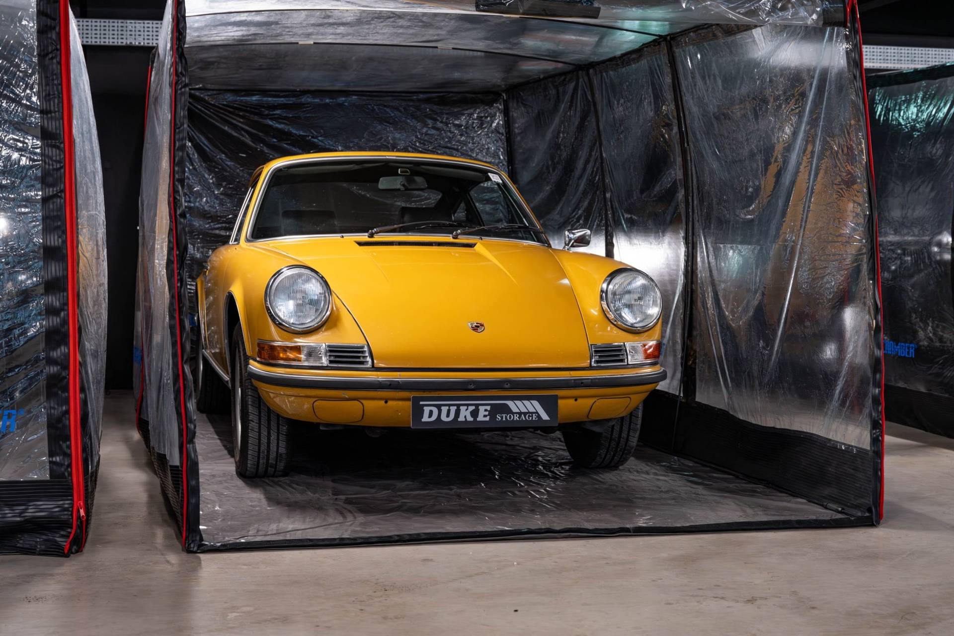 Bright yellow vintage Porsche in a clear storage pod inside a West London car showroom through Love Locations.