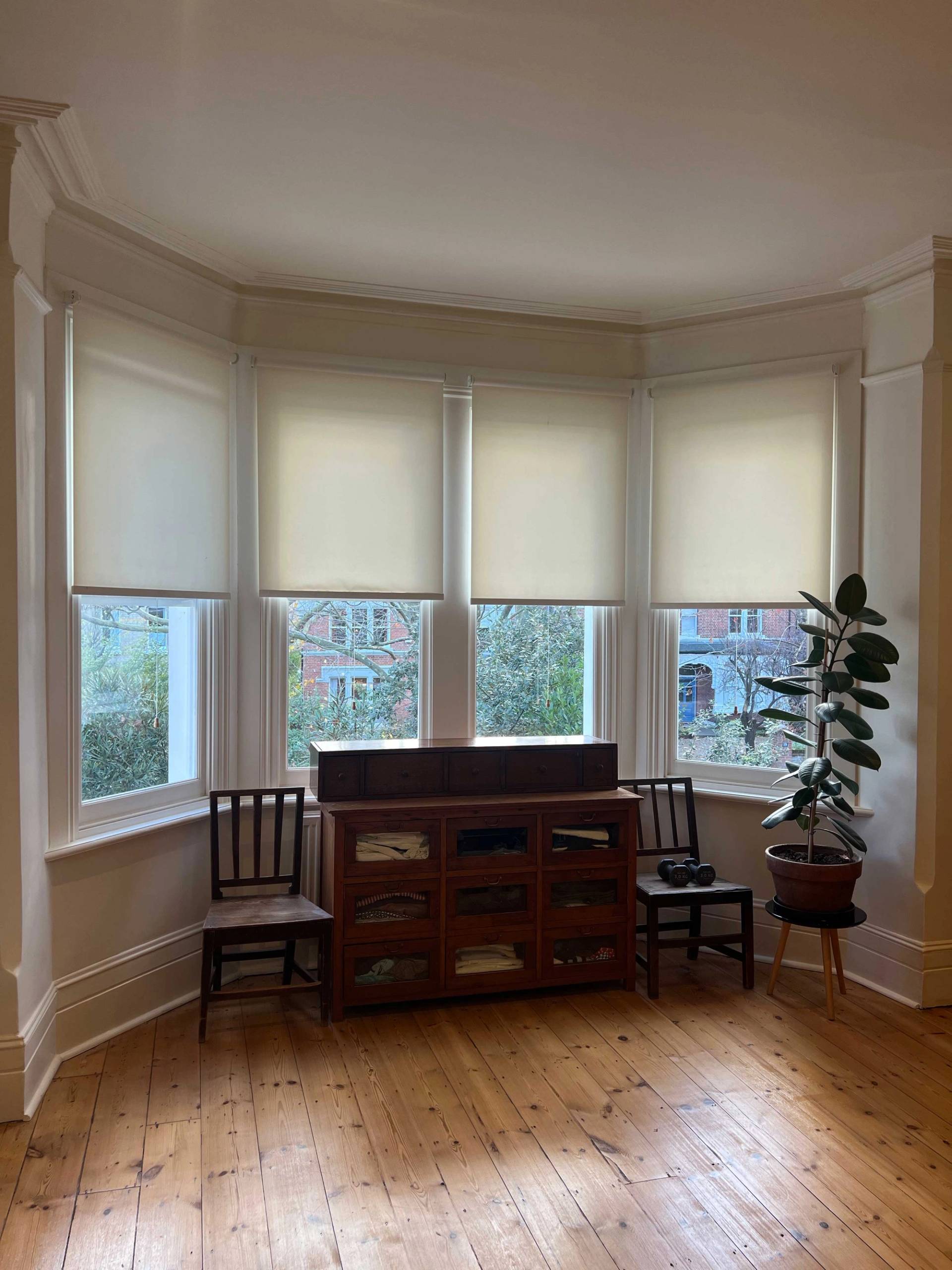 Bay window nook in a master bedroom with dark wood storage cabinet and potted indoor plants, Love Locations SE5.