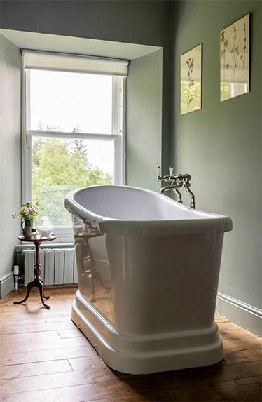Glenstriven free-standing bath by a large window overlooking woodland at the historic country house.