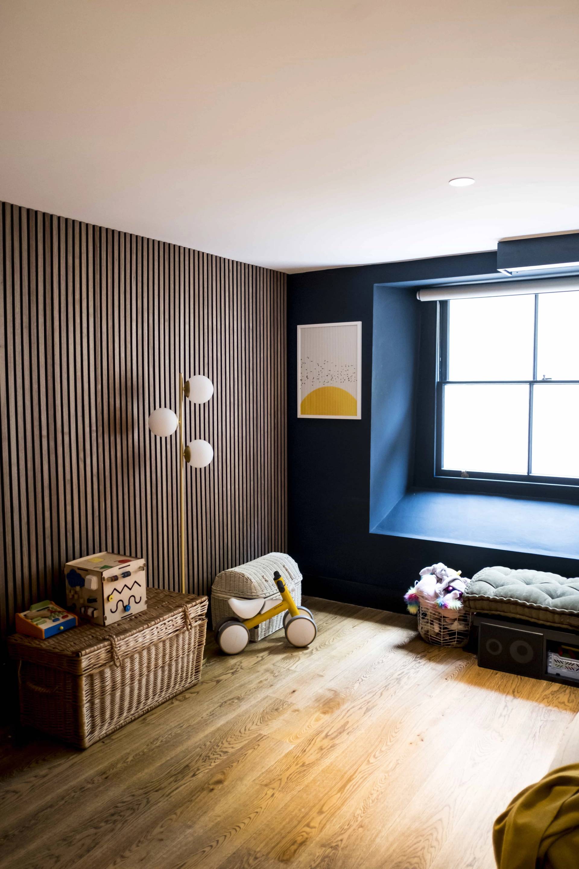Acoustic vertical wood panelling wall feature in a dark blue home office room in SE5 via Love Locations.