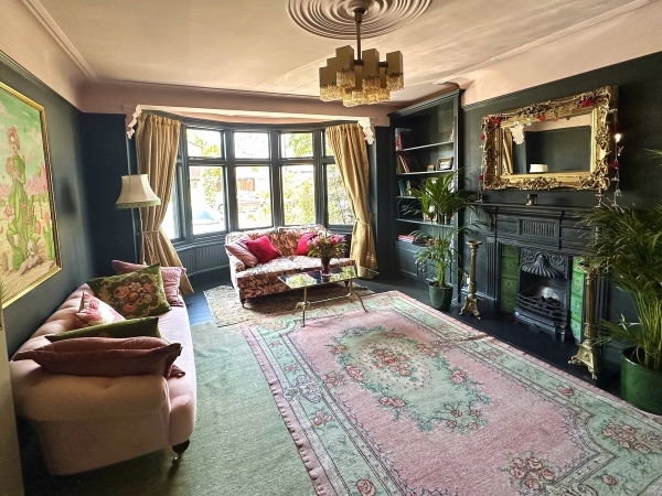Spacious Edwardian reception room with bay window, dark fireplace mantel, and oriental rugs, Love Locations N13.