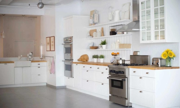 Wide shot of a clean, all-white kitchen setup with professional ovens and white cabinetry in an NYC 10011 loft location, Love Locations.