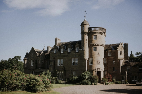 Historic Scottish castle estate facade with circular stone turrets and manicured grounds in Fife, Love Locations KY15.