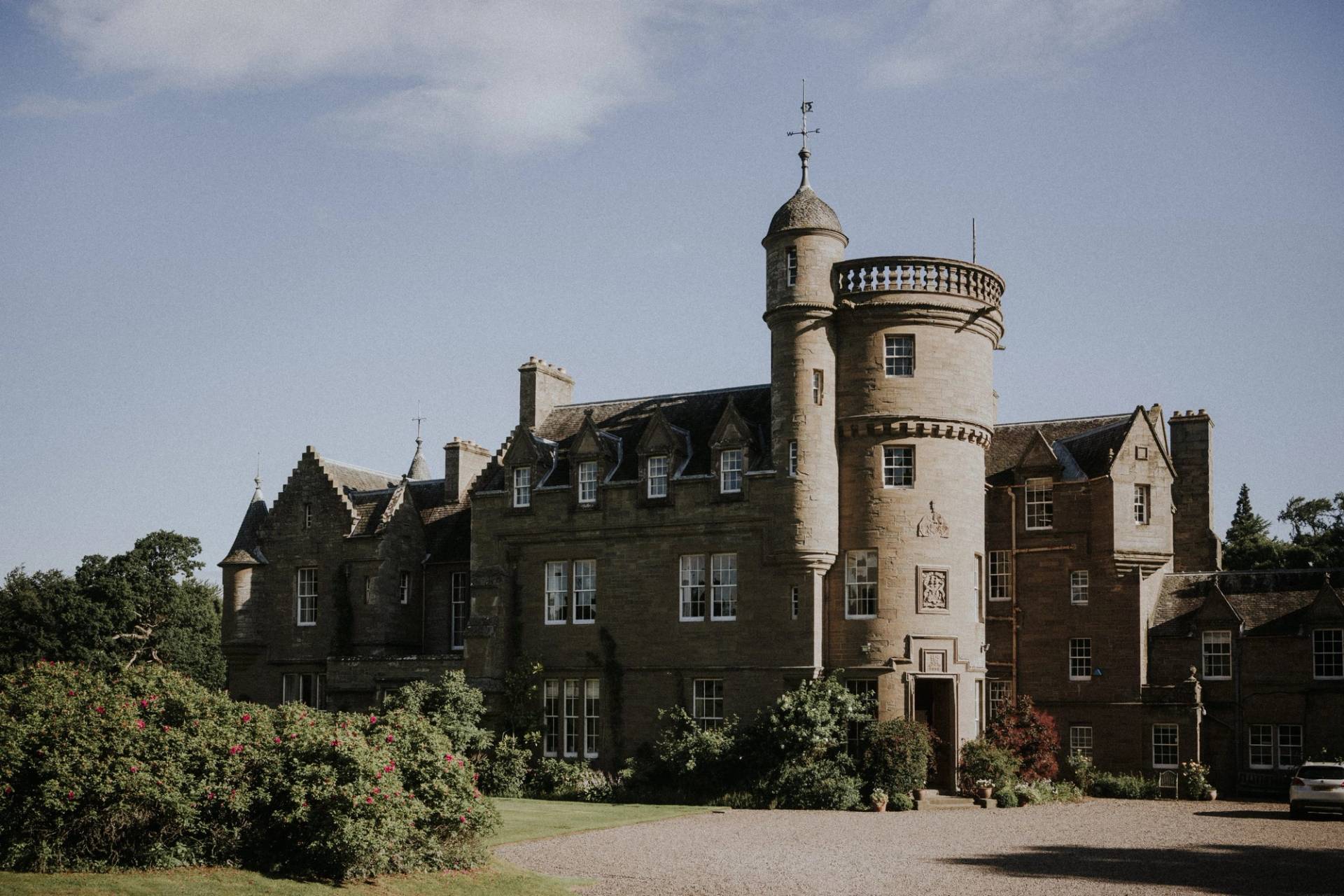 Historic Scottish castle estate facade with circular stone turrets and manicured grounds in Fife, Love Locations KY15.