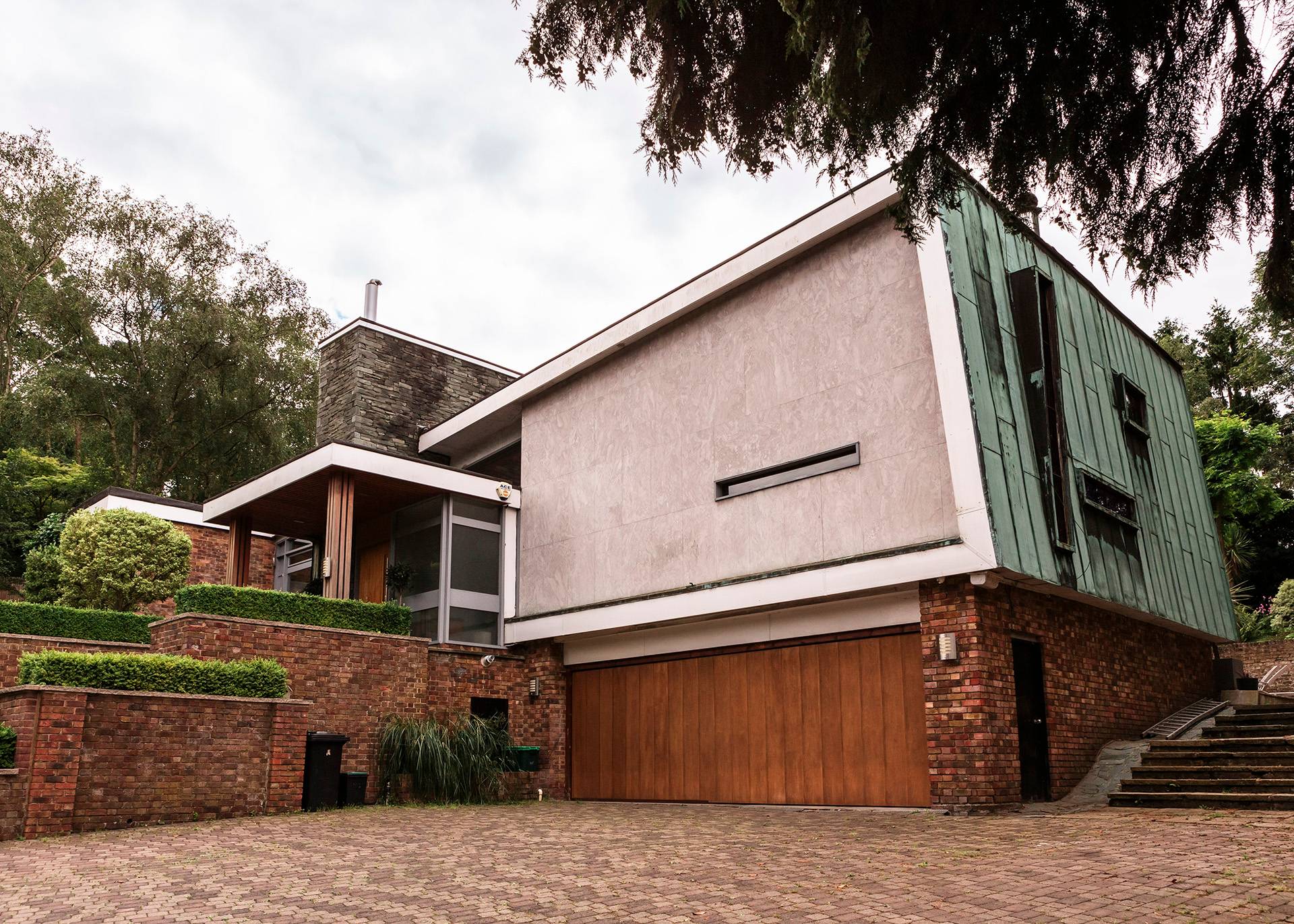 Mid-century modern architectural house exterior shoot location in Bromley, BR1 featuring angled timber cladding, large brickwork, and a private driveway garage, ideal for architectural lookbooks via Love Locations.
