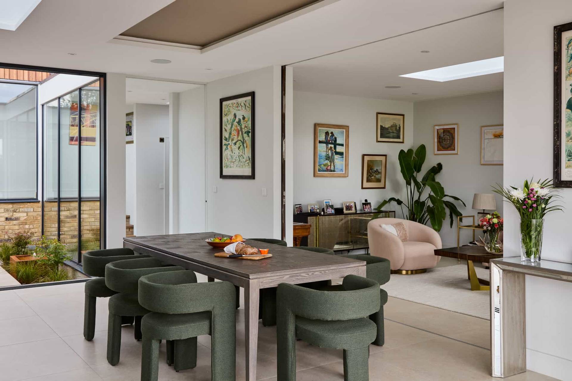 Spacious dining zone featuring a dark wood table, olive green curved chairs, and skylight ceilings in a modern Surrey location home, perfect for luxury homeware lookbooks, Love Locations KT22.