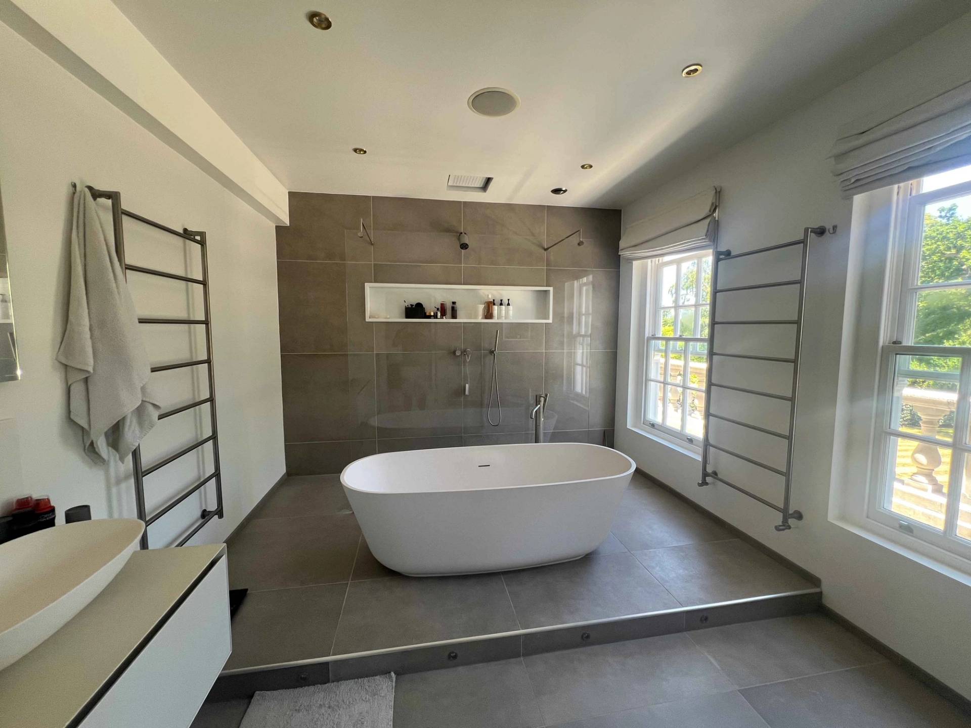 Luxury master bathroom featuring a freestanding oval tub, grey slate wall tiles, and sash window, Love Locations BR7.