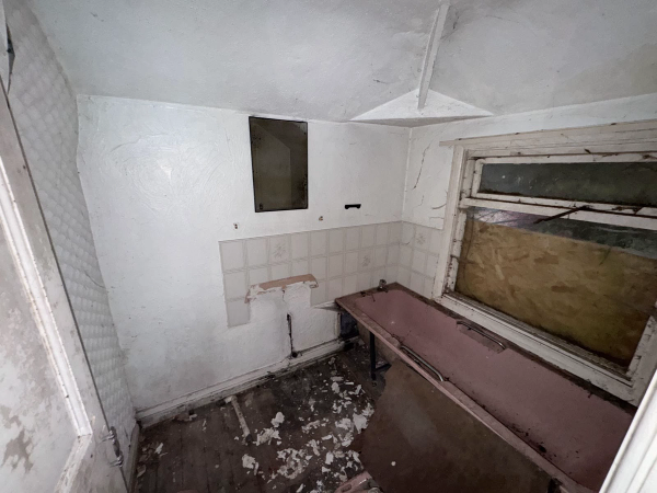 Decaying utility room with peeling tiled walls and old worktops, perfect for horror movie scenes or gritty photography, Love Locations.