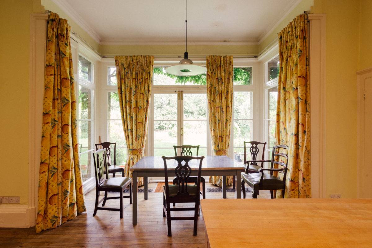 Traditional dining room setup featuring floral curtains, wooden dining table set, and parquet flooring, ideal for family brand advertising, Love Locations.