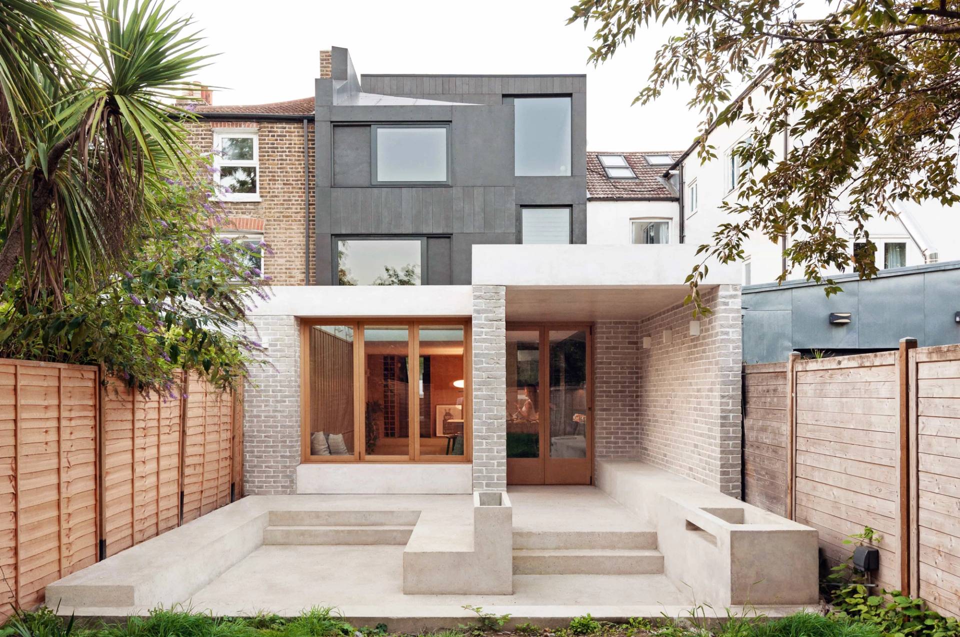 Modernist rear extension courtyard facade shoot location in Hackney London N16 through Love Locations, featuring light grey render, terraced steps, and large timber-framed glass doors.