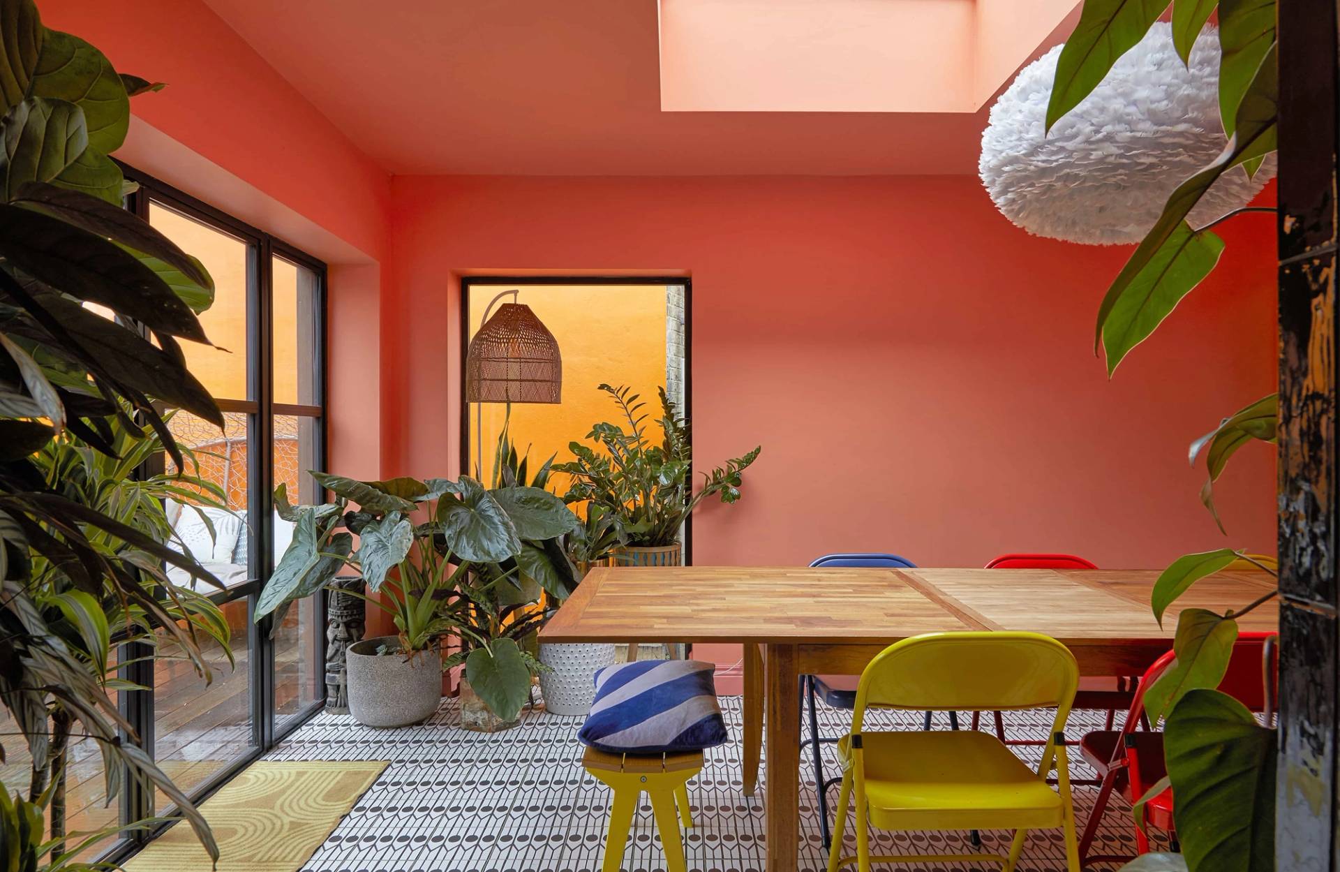 Coral orange dining space with a solid timber table, blue and white striped stools, and large skylight, Love Locations Catford.