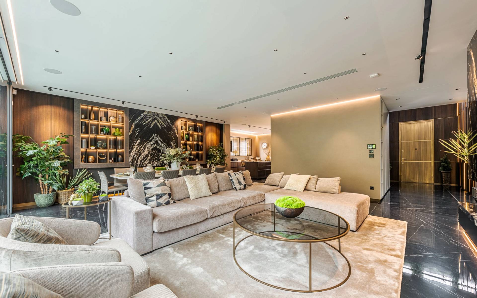 Spacious reception room with soft grey sectional sofa, ambient lighting, and dark marble flooring, Love Locations SW11.