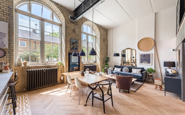 Double-height apartment location house featuring exposed brick walls and massive arched Victorian windows, curated by Love Locations.