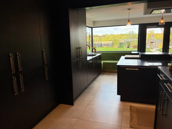 Contemporary black kitchen location house for film and commercial shoots in Essex CM4 from Love Locations, with dark cabinetry and window views over rolling green hills.
