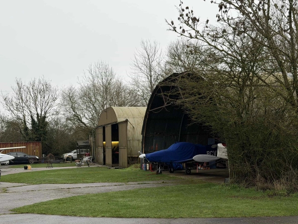 Curved aircraft shelter and hangar entrance showing a blue-covered plane, perfect for behind-the-scenes film production crews, Love Locations.