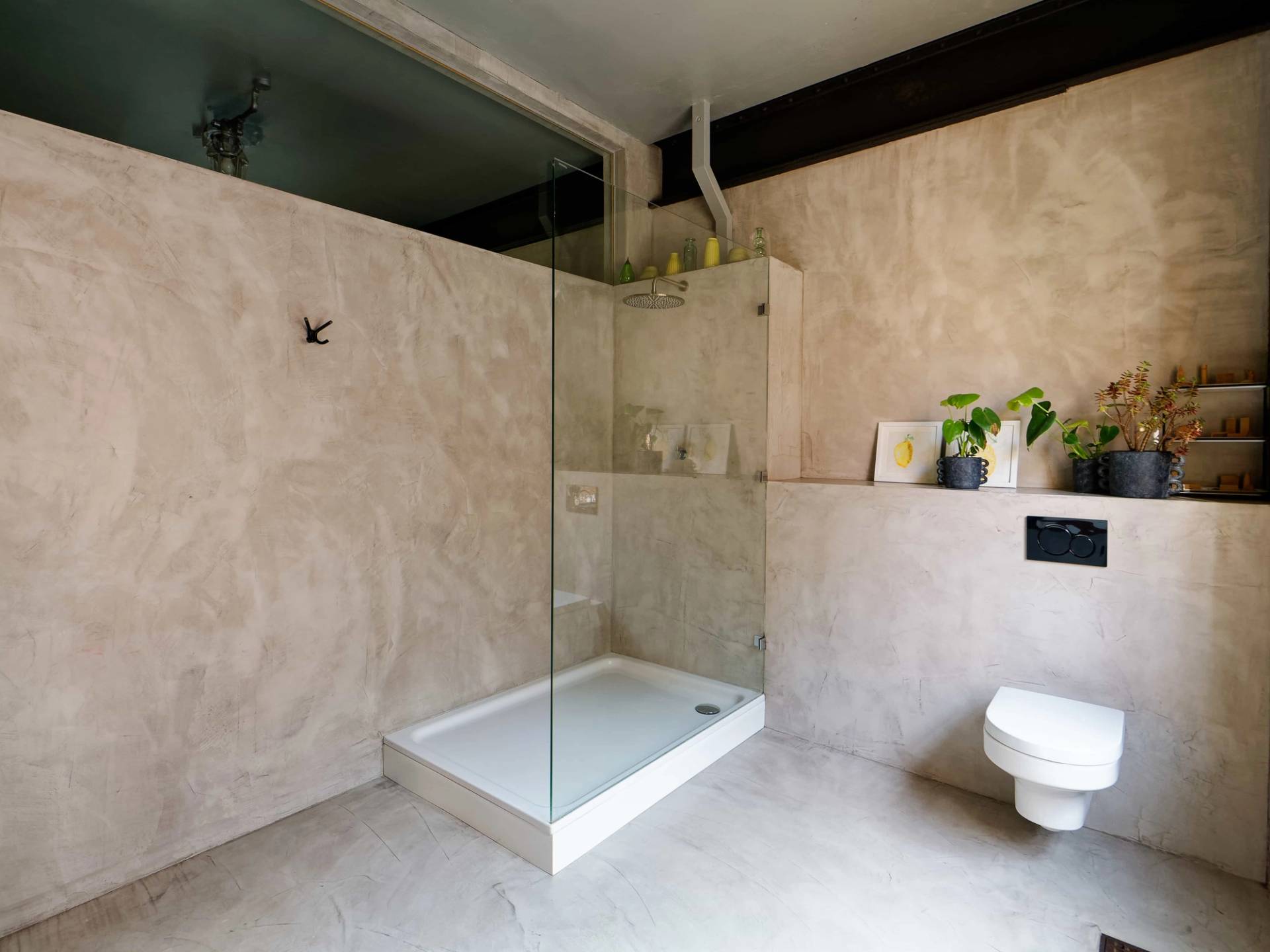 Modern micro-cement bathroom featuring a walk-in shower with glass screen and polished concrete walls, Love Locations E14.