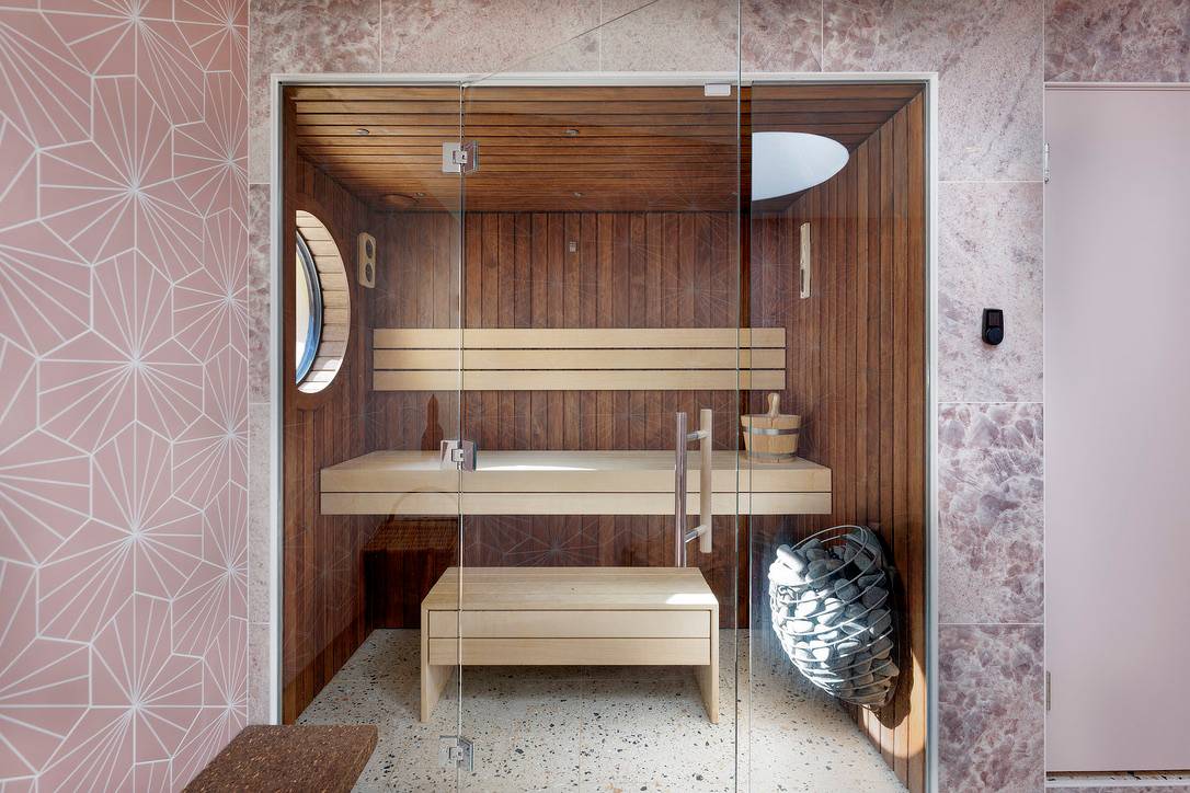 Luxury timber-lined Finnish sauna room featuring slatted wood benches and glass door, Love Locations OX7.