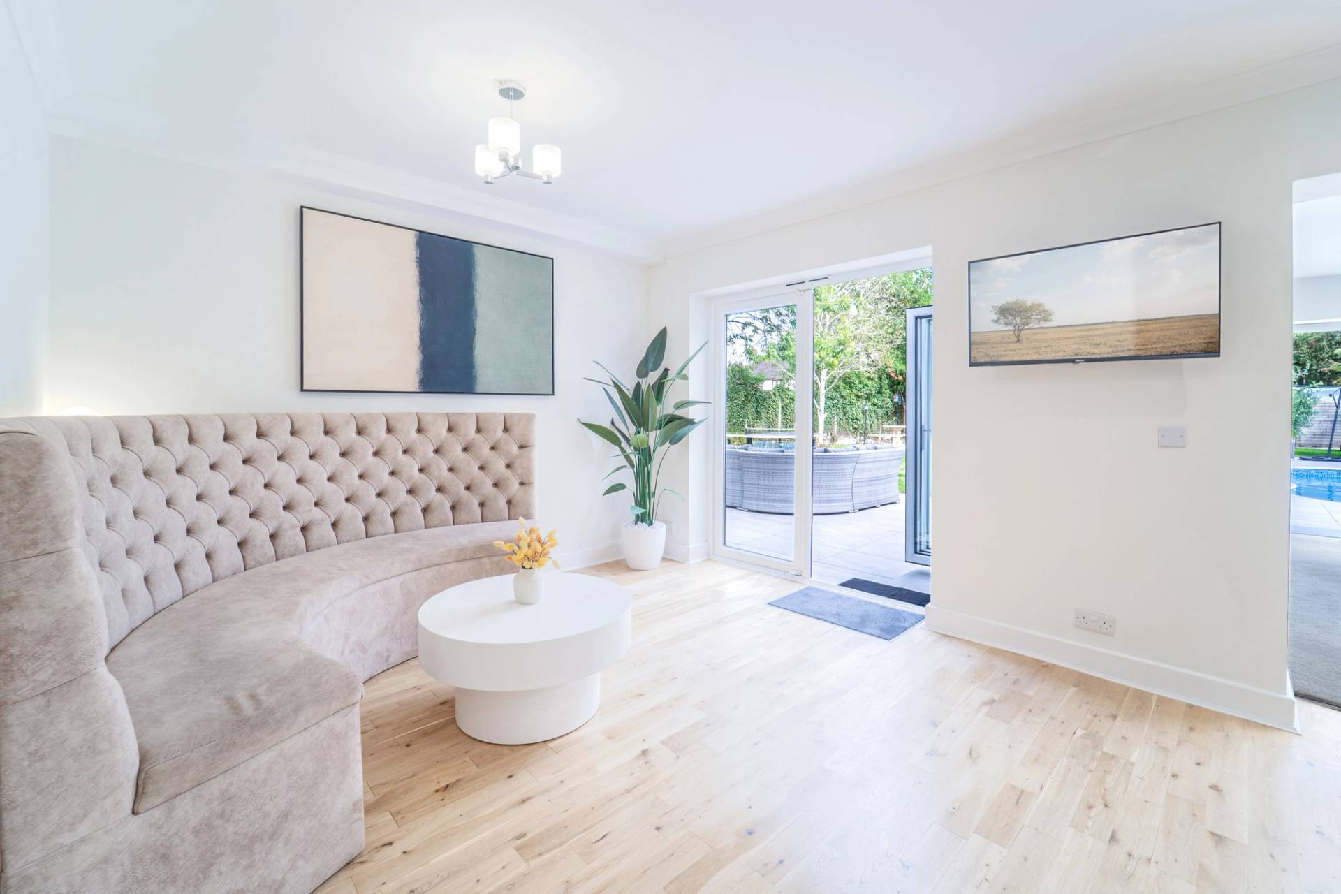 Sunlit reception seating area with cream upholstery, white round coffee table, and patio doors, Love Locations RM11.