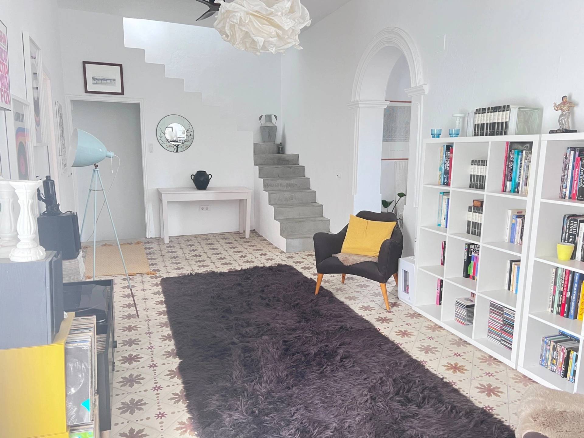 Grand living hall film location in Jimena de la Frontera Cádiz through Love Locations, featuring traditional Spanish patterned floor tiles, white arches, dark armchairs, and a large rug.