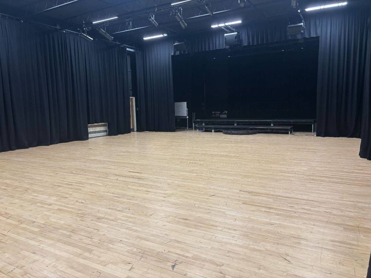 School drama studio and performance space filming location with black perimeter curtains and polished wooden floor through Love Locations.