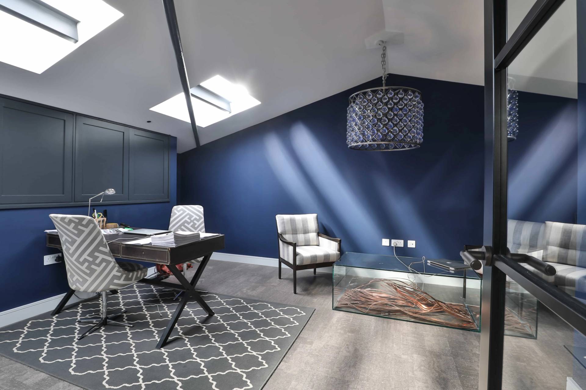 Home office study desk set under sloped roof ceilings with skylight illumination and dark blue walls, Love Locations CV23.