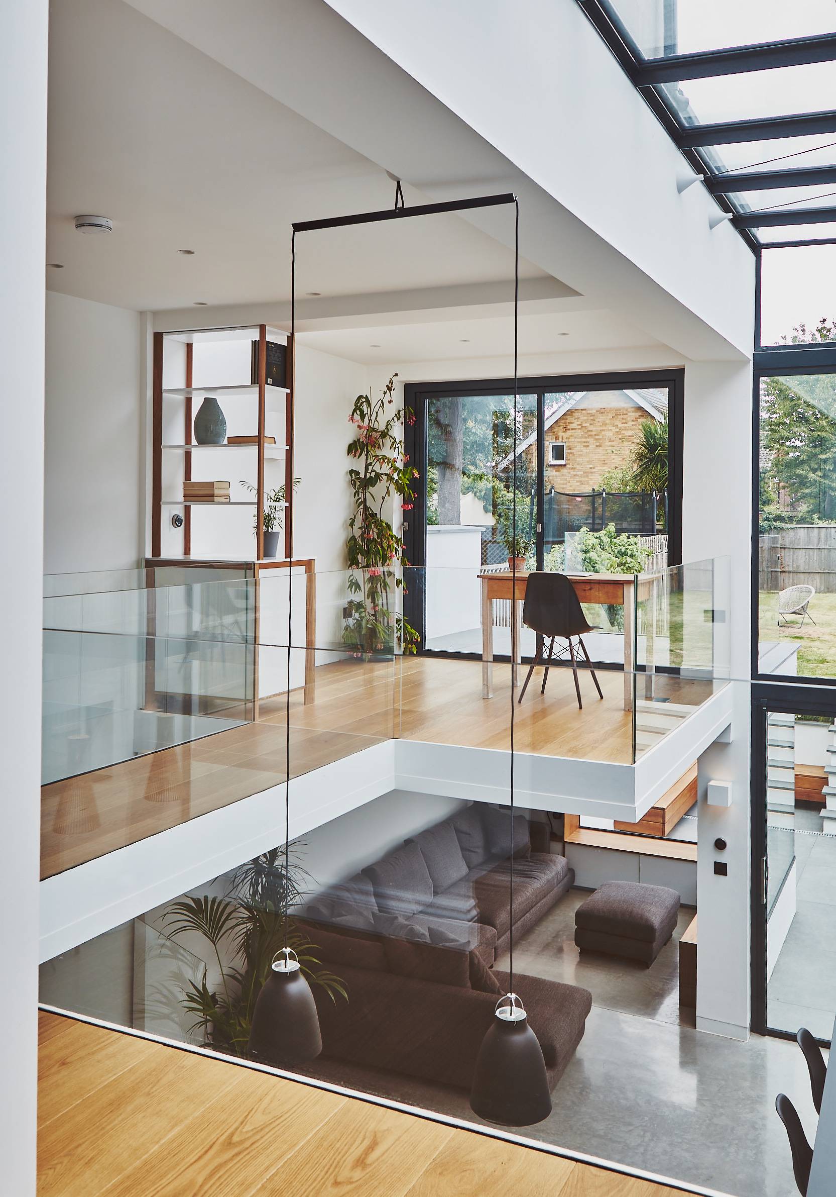 Galleried upper floor bridge with glass railings looking down into a double-height kitchen void, Love Locations TW1.