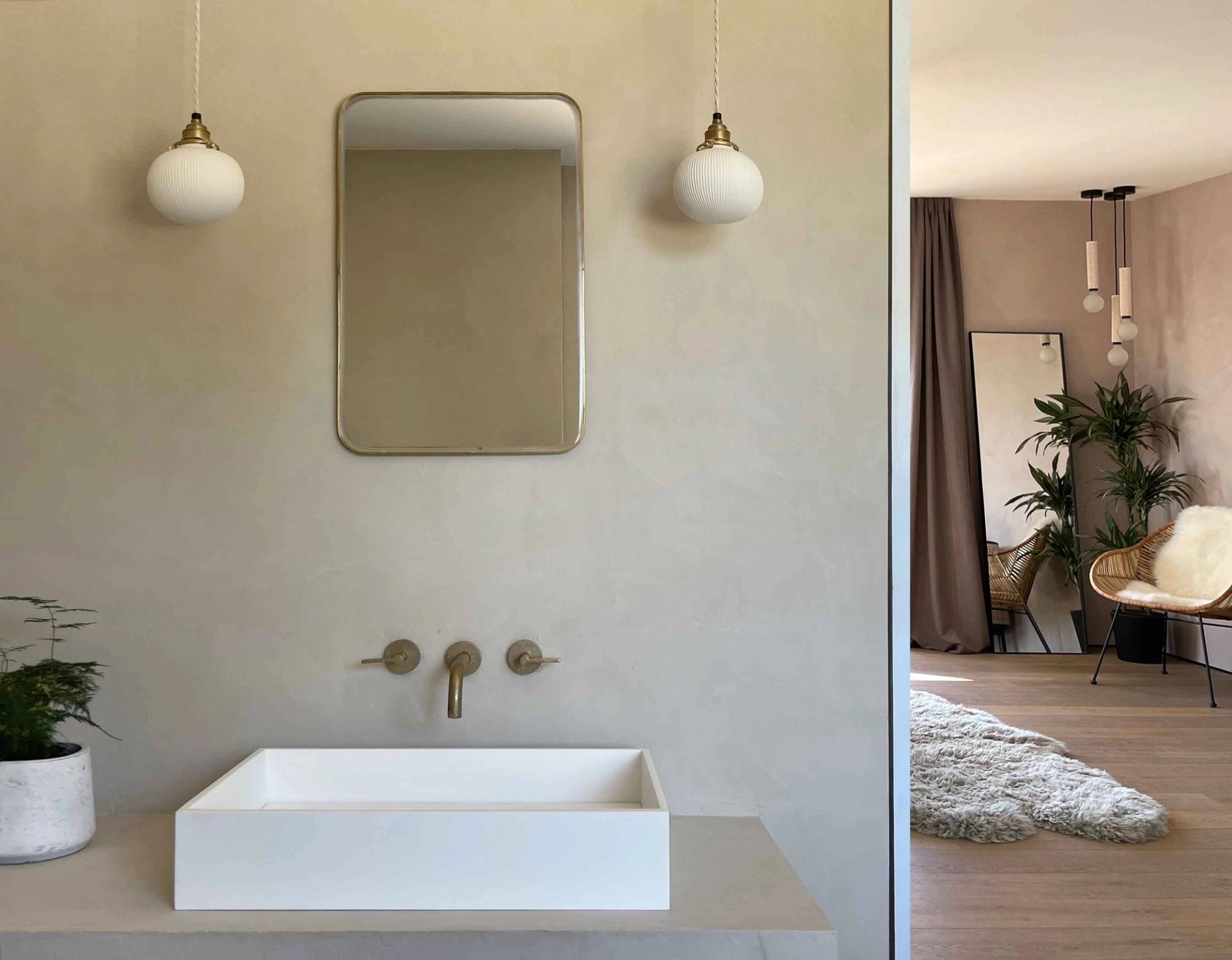 Contemporary ensuite bathroom featuring a wall-mounted brass tap, countertop sink basin, and neutral plaster walls, ideal for skincare product marketing, Love Locations.