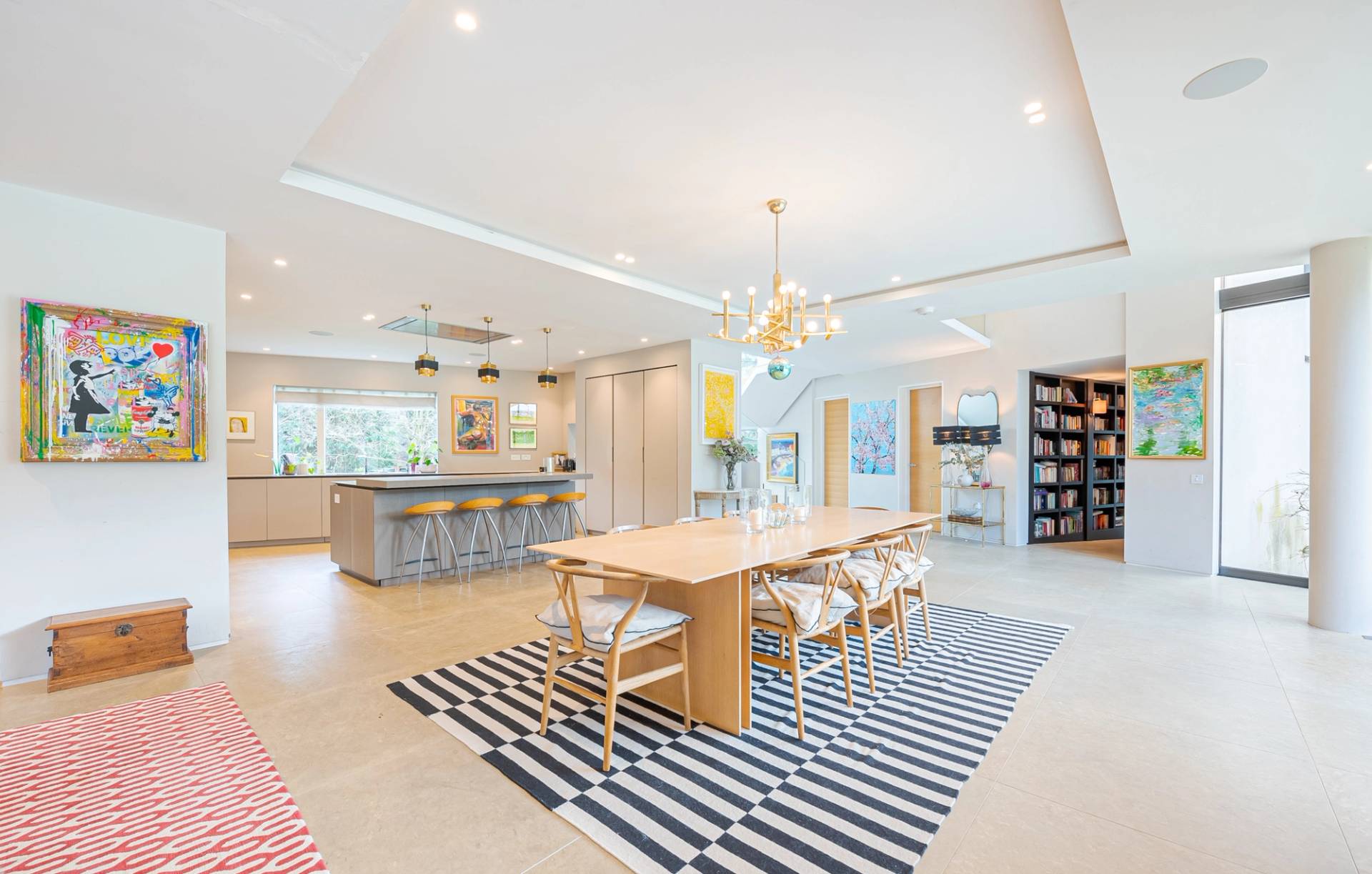 Contemporary luxury open-plan dining room shoot location in Kingston upon Thames, KT2 featuring a large wooden table, striped rug, and marble kitchen island via Love Locations.