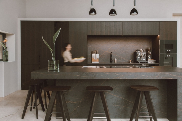 Modern luxury villa location in Mallorca, 07630 featuring a dark textured kitchen island counter, bar stools, and black pendant lights via Love Locations.