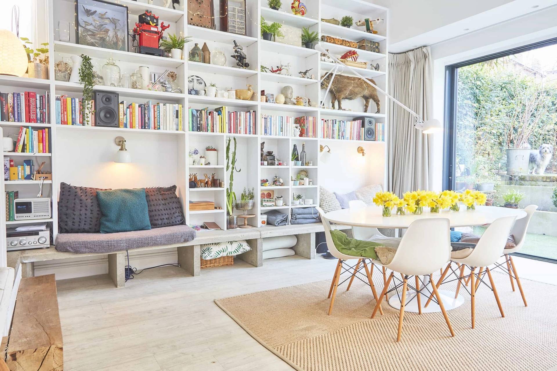 Dining nook in an open-plan extension featuring a full-wall white grid bookcase, oval table, and Eames-style chairs, ideal for editorial shoots, Love Locations.