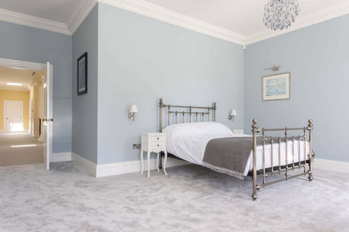 Traditional period bedroom featuring a classic wrought iron bed frame and elegant mouldings, available for hire on Love Locations.