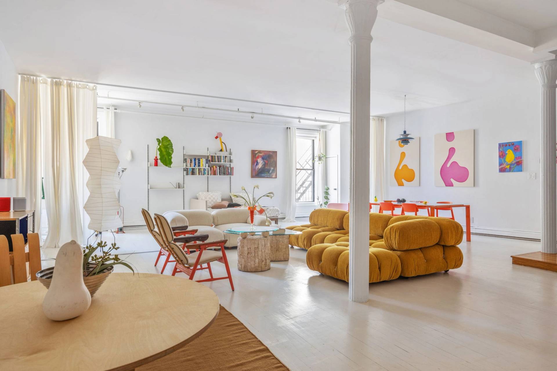 Spacious white loft reception area available through Love Locations in Tribeca New York, featuring cast-iron columns, mustard seating, and polished white floors.