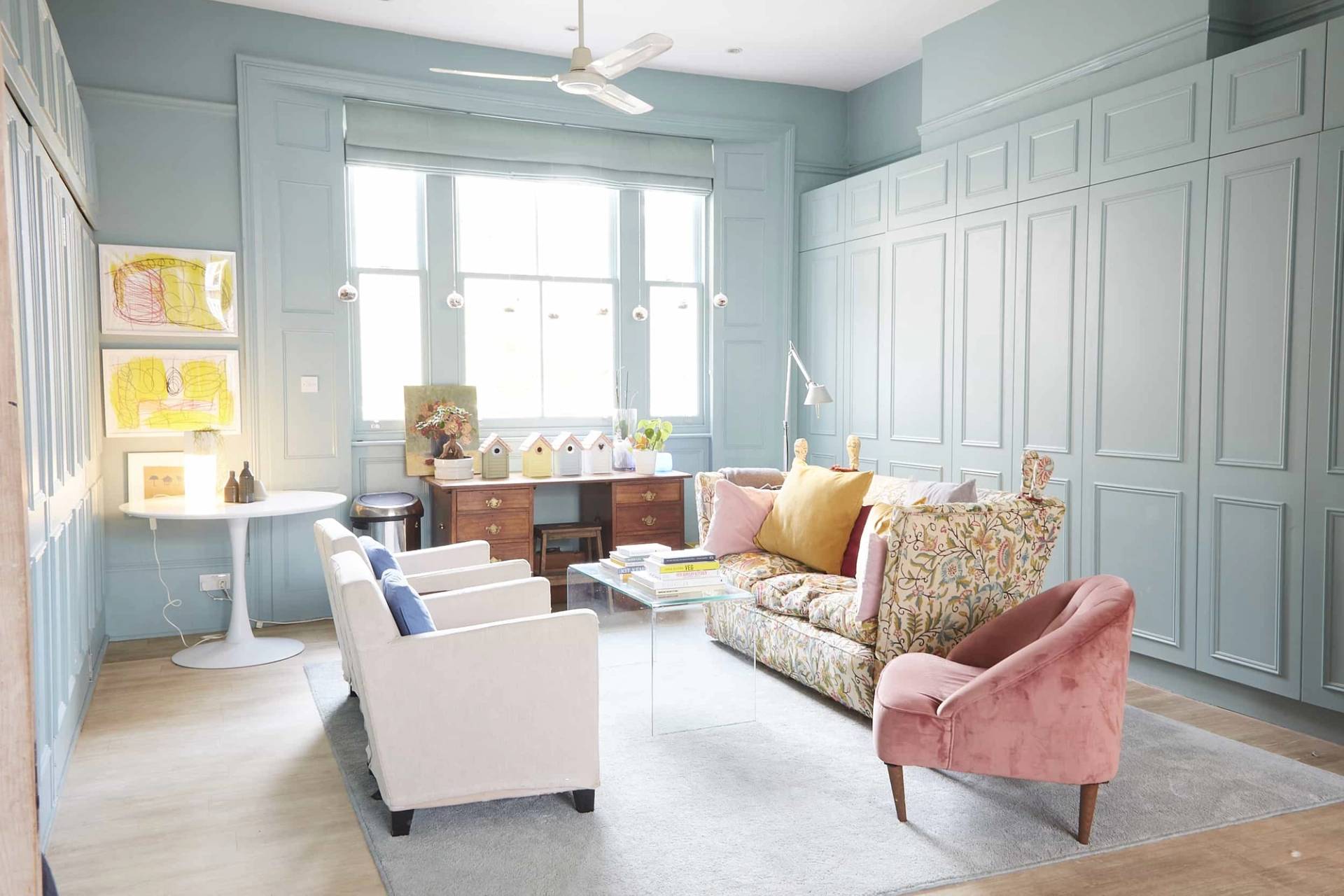 Duck-egg blue painted living room with floor-to-ceiling wainscoting panelling, sash window shutters, and plush pink velvet armchair, Love Locations N5.
