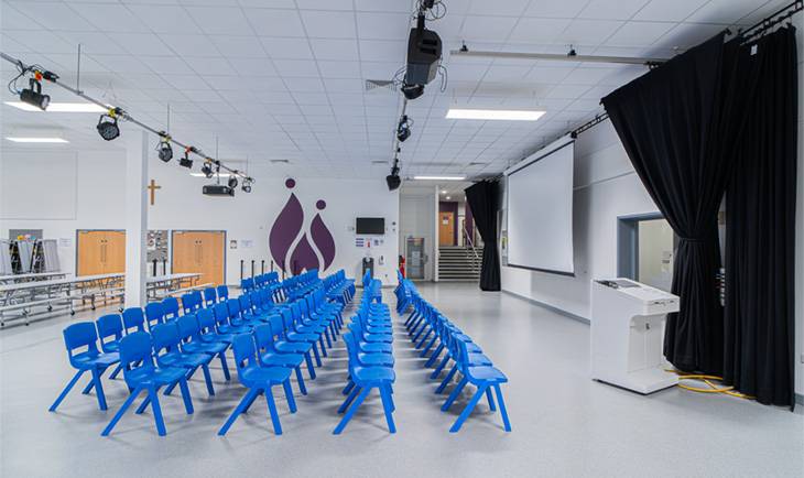 Versatile multi-purpose school hall production location showing clean white walls, stage lighting track, and seating setup from Love Locations.
