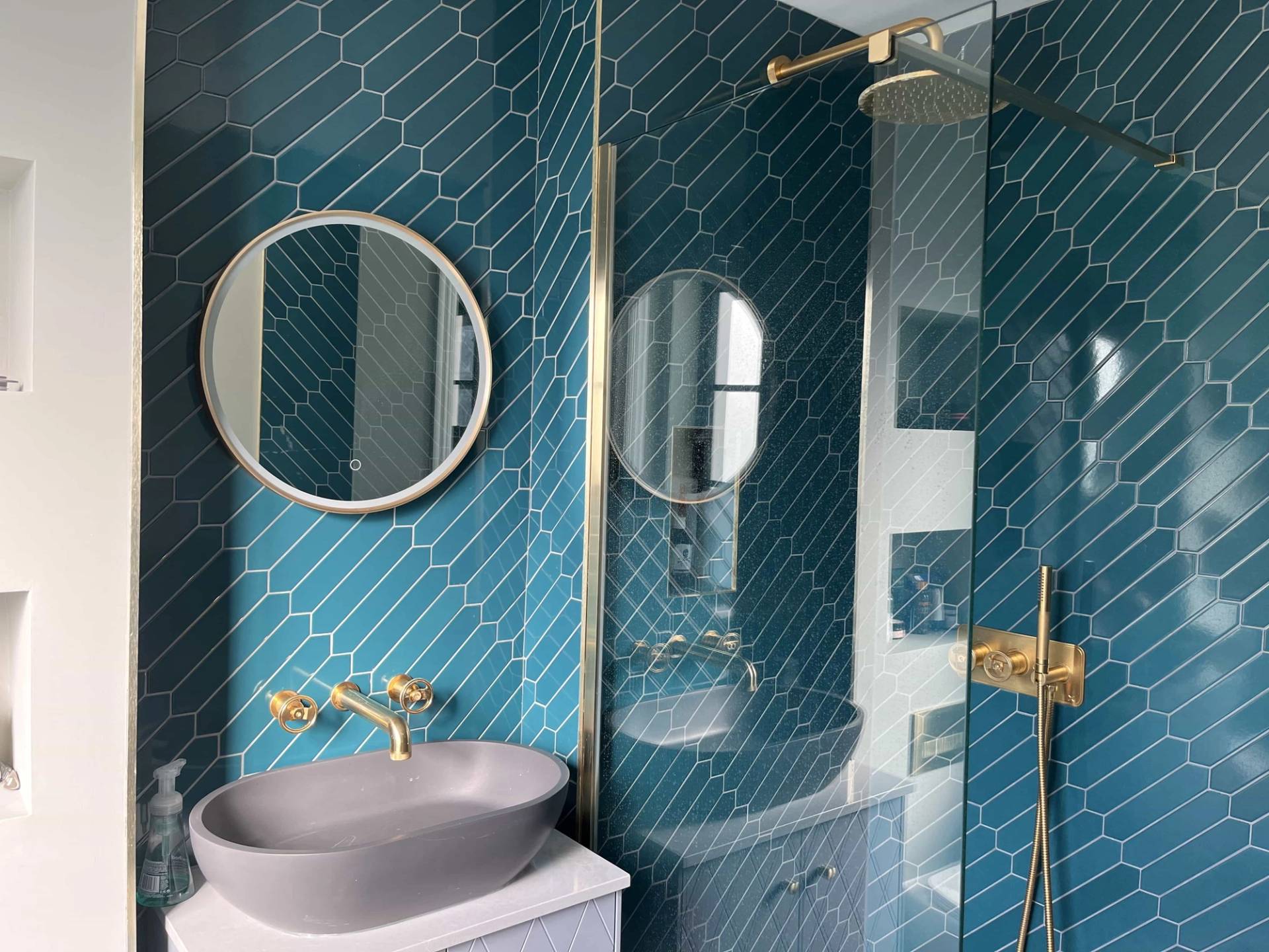 Luxury ensuite bathroom featuring teal chevron wall tiles, vessel sink, and gold vanity fittings, Love Locations GU3.