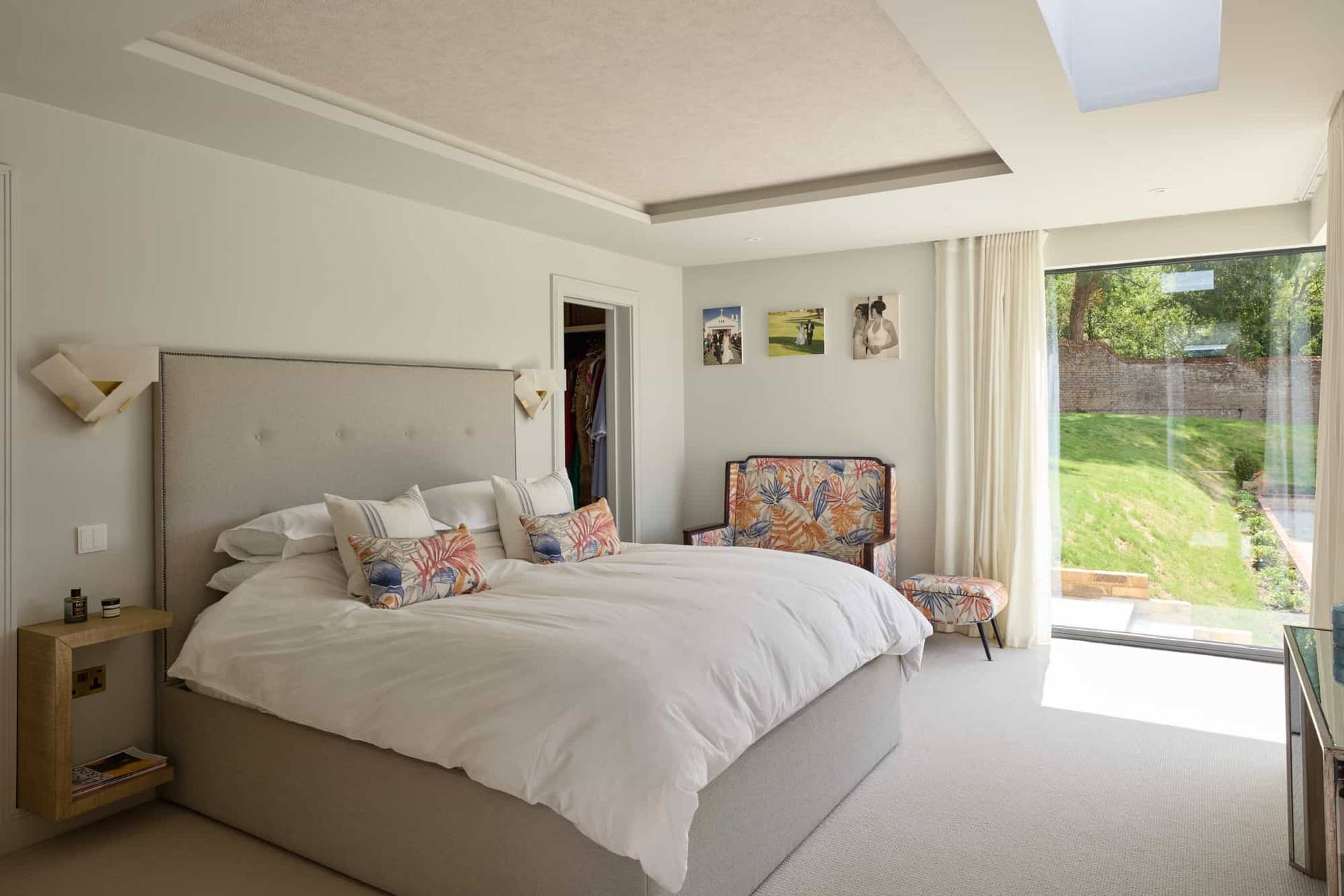 Spacious master bedroom suite featuring a grey upholstered bed, patterned accent armchair, and direct patio garden access, perfect for sleepwear and mattress ads, Love Locations KT22.