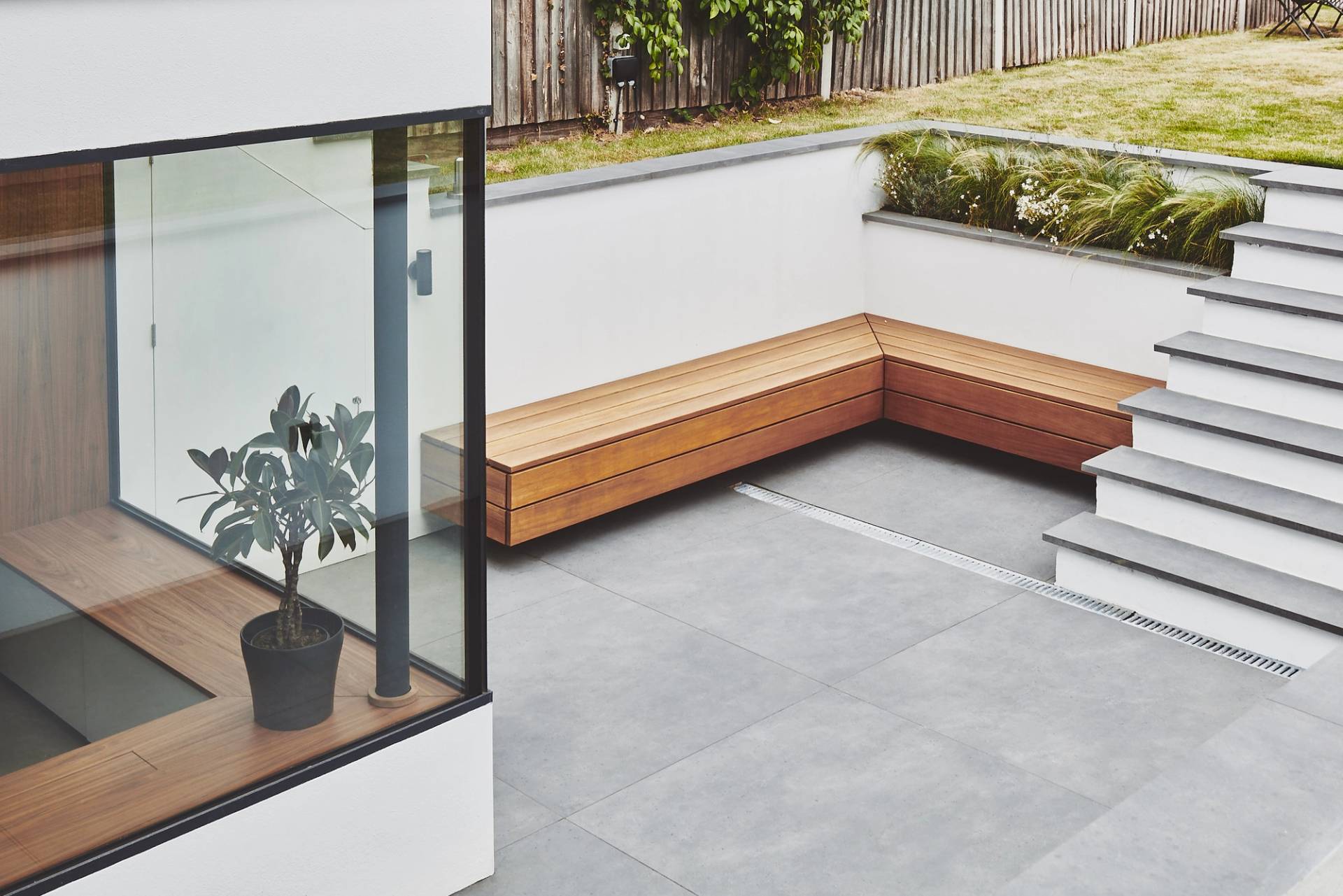 Sunken outdoor patio terrace featuring a built-in wooden corner bench and slate paving, Love Locations TW1.