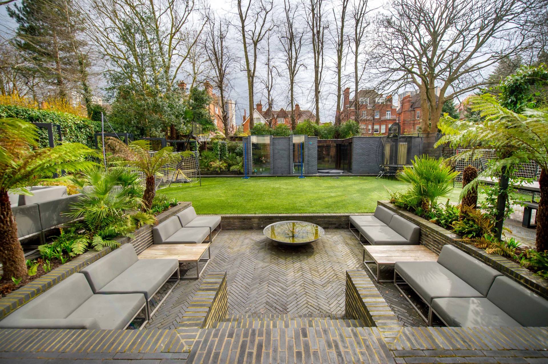 Sunken stone patio terrace featuring wrap-around modular outdoor seating and a modern fire bowl feature, Love Locations.