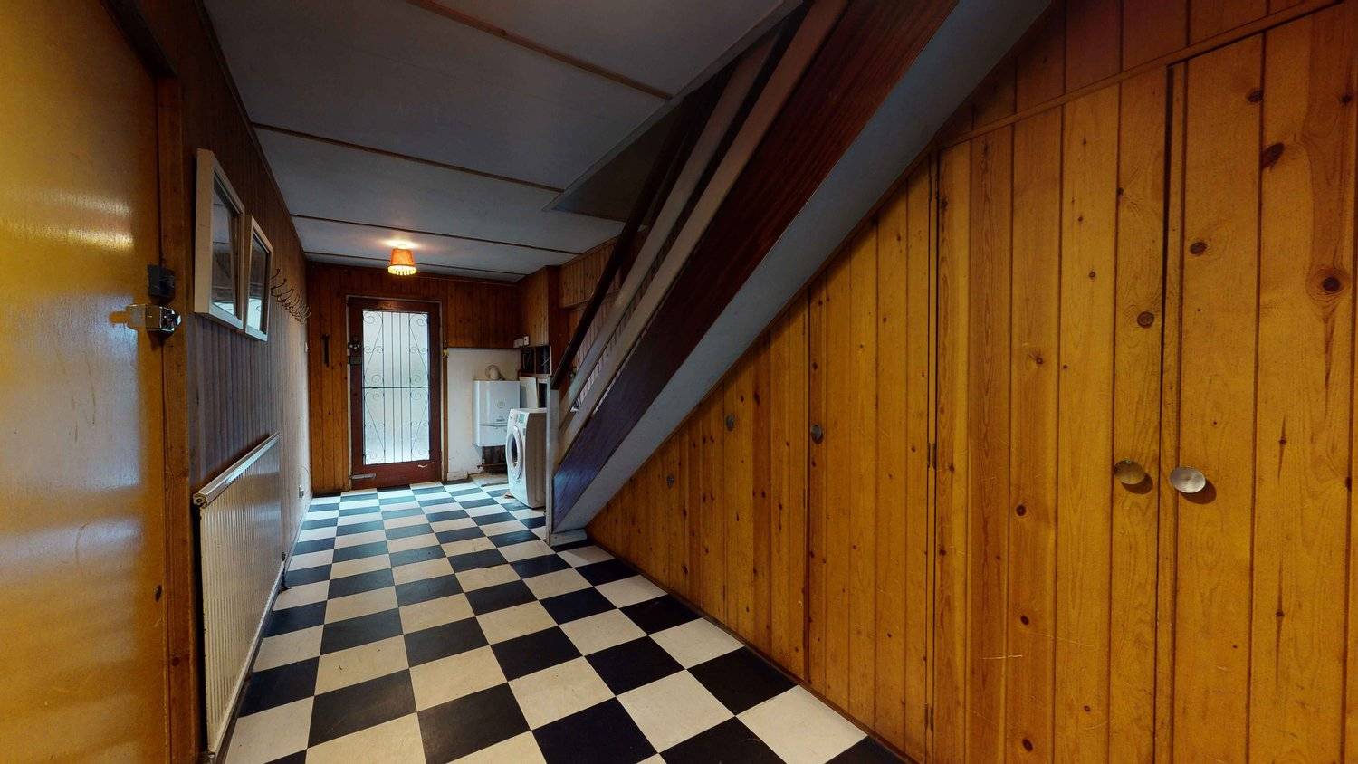 Retro entrance stairwell featuring wood-panelled walls and black and white checkerboard floor tiles, Love Locations SW16.