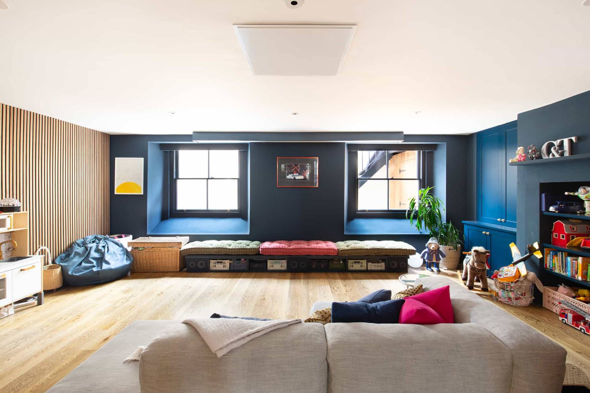 Dark blue media room with built-in low seating bench and large sash windows in Camberwell, SE5 via Love Locations.