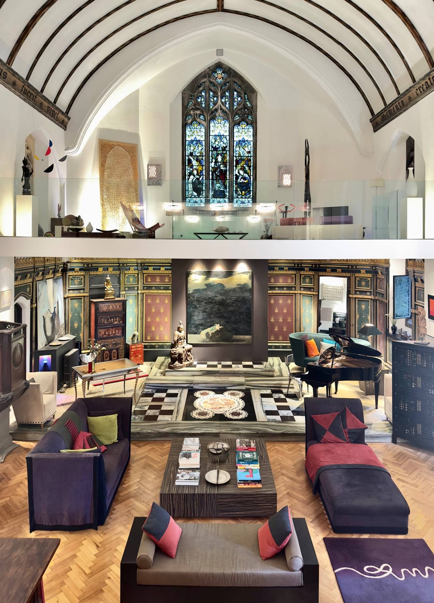 Symmetrical view of the main double-height reception hall inside a chapel conversion shoot location in Oval SE5 via Love Locations, showcasing gothic arched windows and dark wood features.