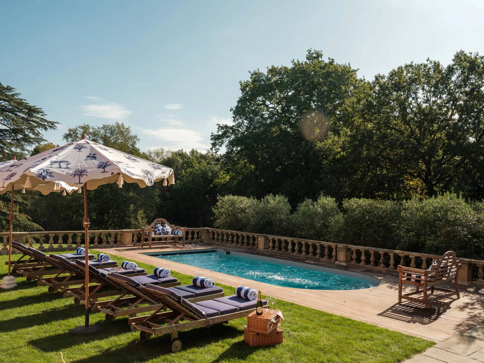 Sunlit swimming pool area on a private estate surrounded by green lawns and mature trees, Love Locations RG42.