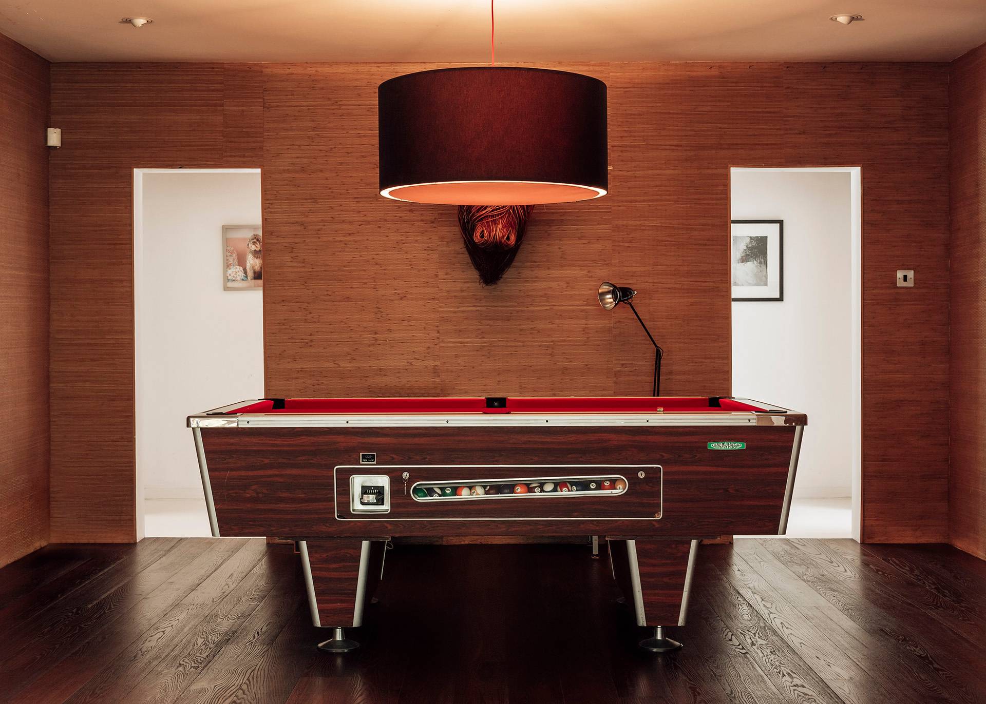 Vintage arcade or games room table featuring retro styling under a dark drum pendant light, ideal for music video shoots via Love Locations.