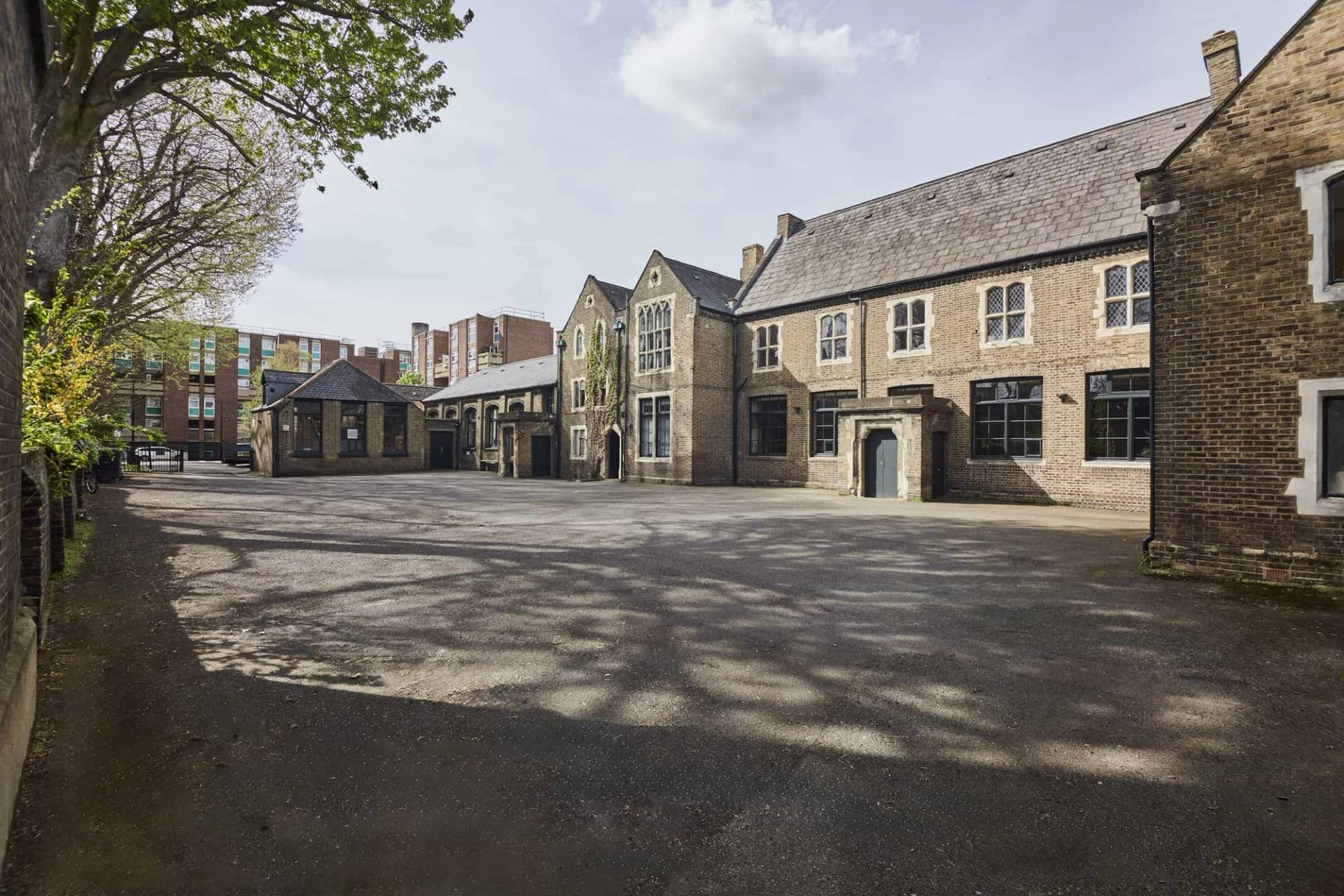 Spacious cobble and asphalt courtyard surrounded by historic stone architecture in East London, Love Locations E2.