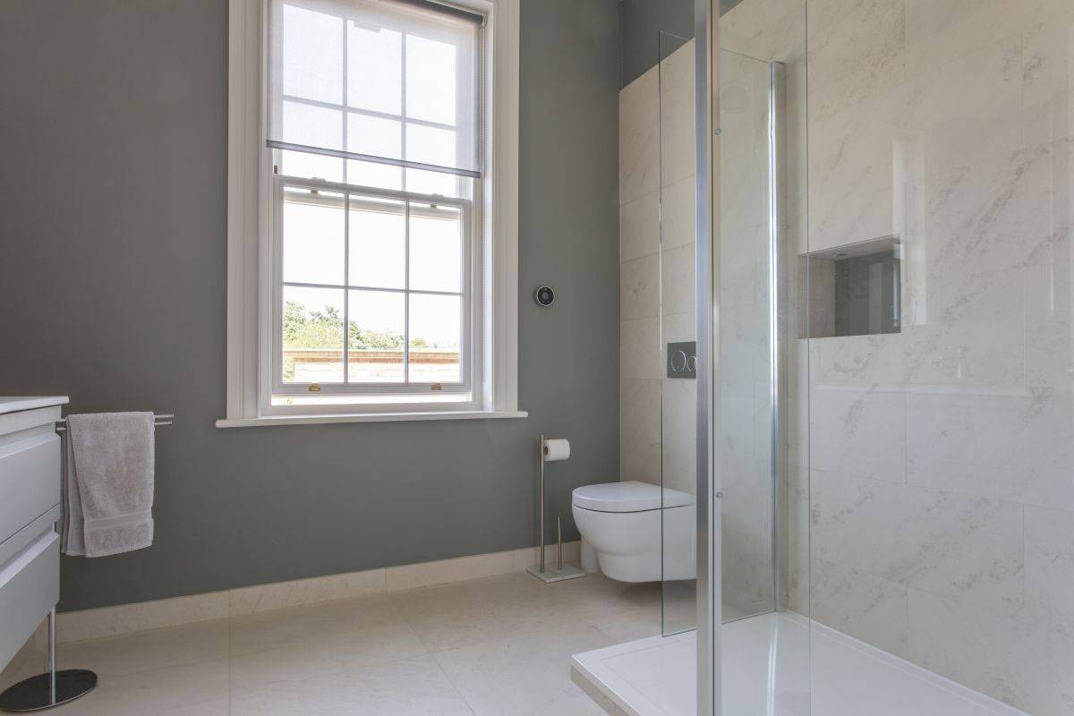 Sleek, minimalist grey bathroom with a large sash window and walk-in shower for commercial shoots, curated by Love Locations, Haywards Heath.