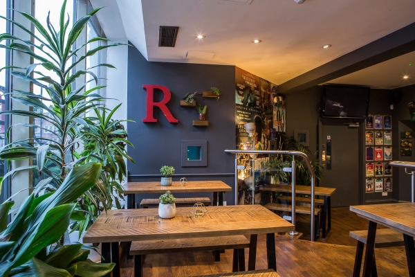 Rustic wooden dining table setup in a cafe corner featuring a bold red 'R' letter prop and vibrant interior styling at The Ritzy SW2, ideal for pop-up food photography, Love Locations.