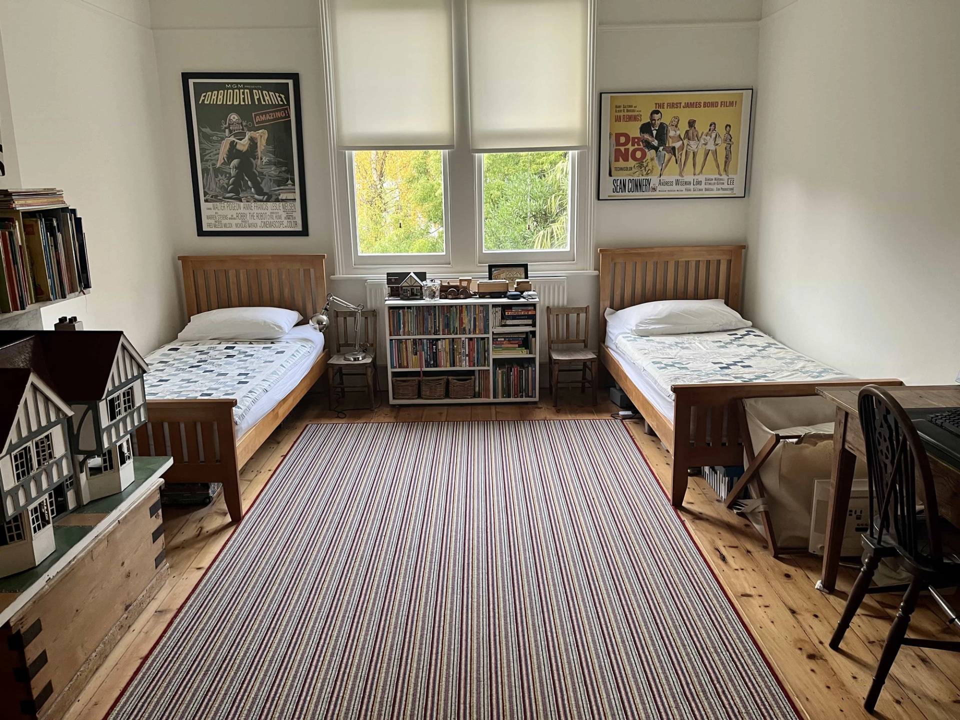 Twin bedroom location featuring stripped pine floorboards, dark wood twin bed frames, and striped area rug, Love Locations SE5.