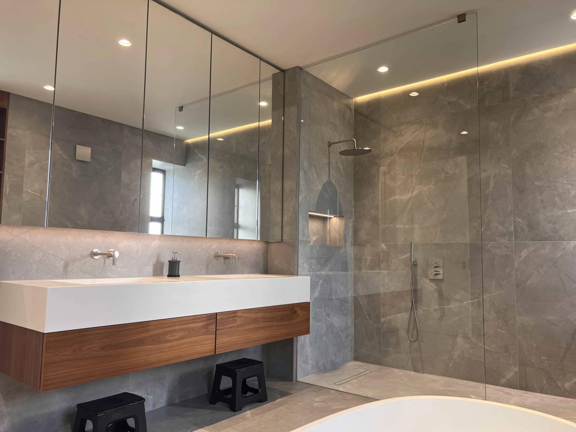Modern guest bathroom featuring a floating dark timber vanity, grey stone tiling, and walk-in glass shower, Love Locations.