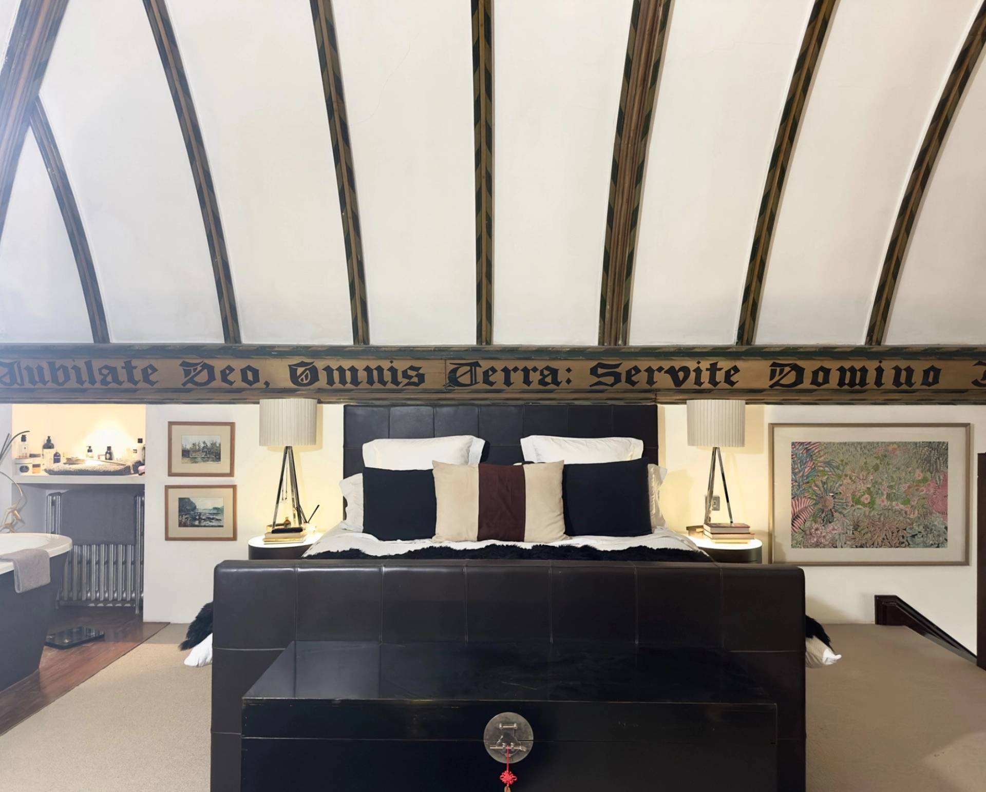 Bedroom interior with vaulted ceiling beams and traditional Latin inscriptions painted on white walls in Oval SE5 by Love Locations.